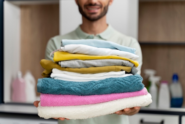 Free photo man holding a pile of clean clothes