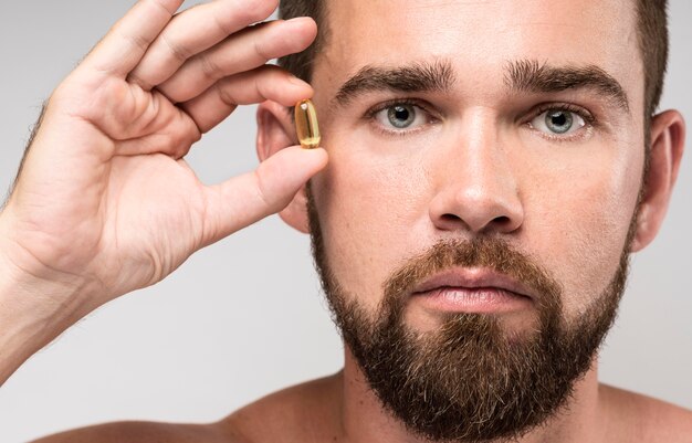 Man holding a pill next to his face