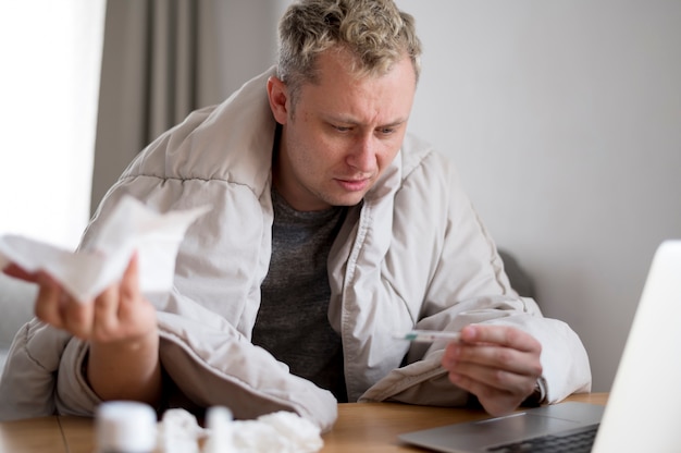 Man holding pills and sitting the the desk front view