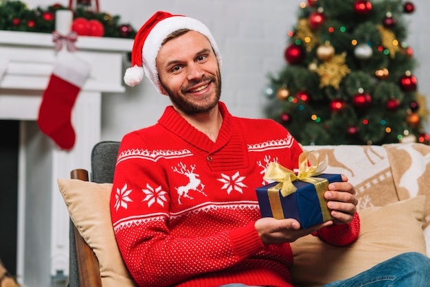 Free photo man holding present box on sofa