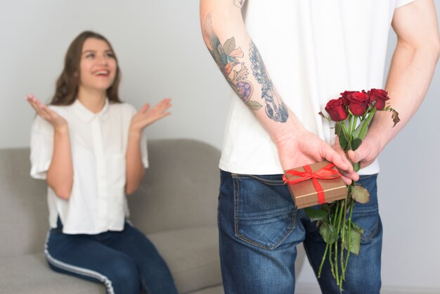 Man holding present for young woman behind back