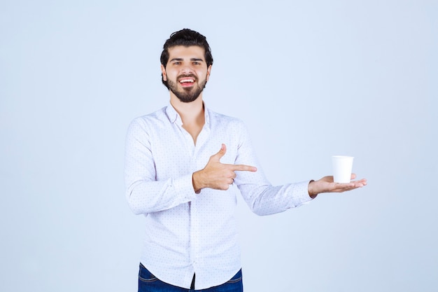 Uomo che tiene e promuove una tazza di caffè o un caffè