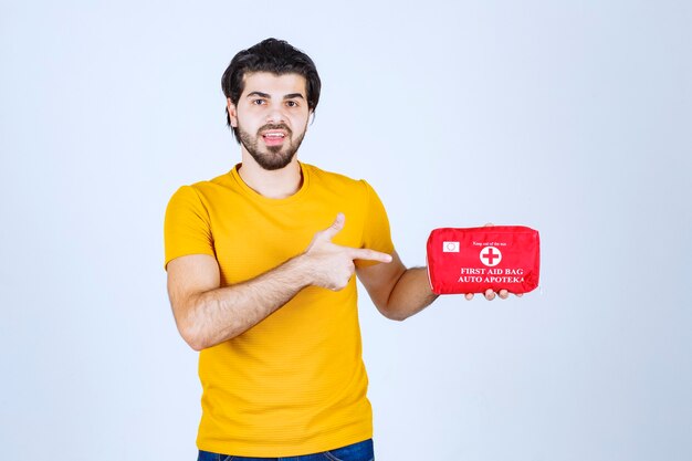 Man holding and promoting a red first aid kit.