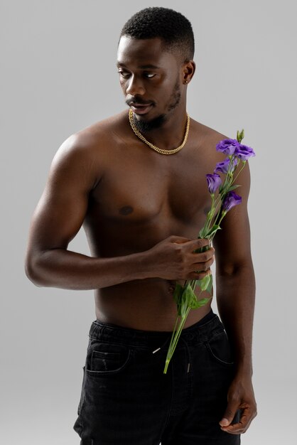 紫色の花のミディアムショットを保持している男