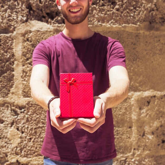 Man holding red gift box again wall