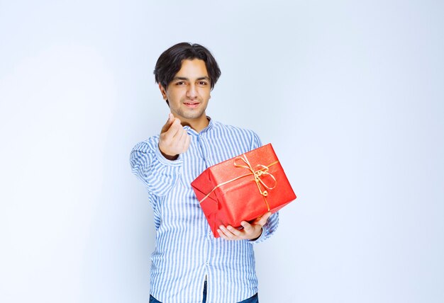 Man holding a red gift box and asking for money. High quality photo