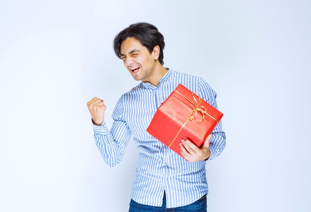 Man holding a red gift box and feeling successful. High quality photo