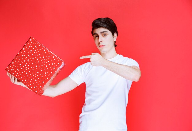 Man holding a red gift box and pointing at it