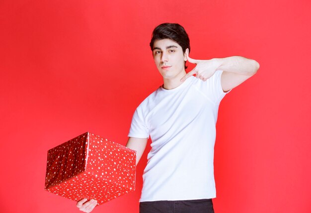 Man holding a red gift box and pointing at it