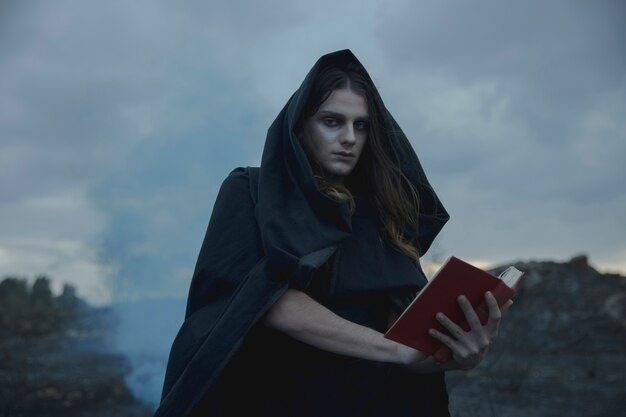 Man holding a red spell book and looking at camera