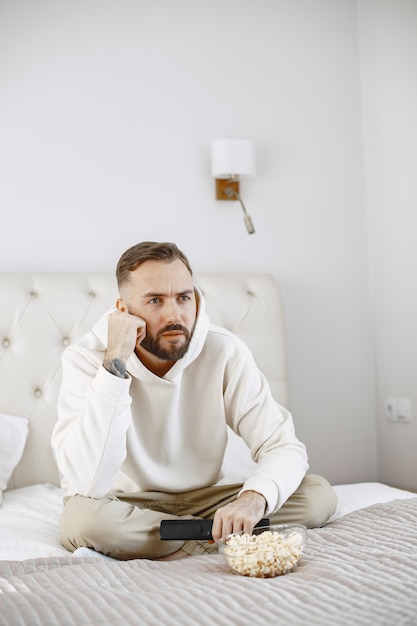 Man holding remote control with popcorn bowl