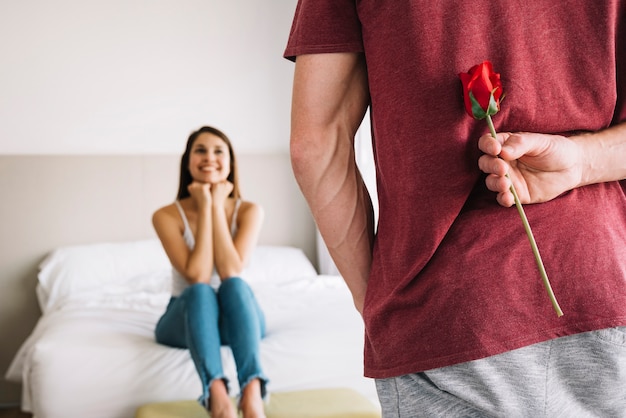 Man holding rose behind back 