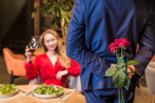 Free photo man holding roses bouquet behind back