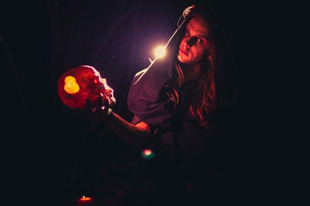 Man holding a skull in the dark and looking at camera