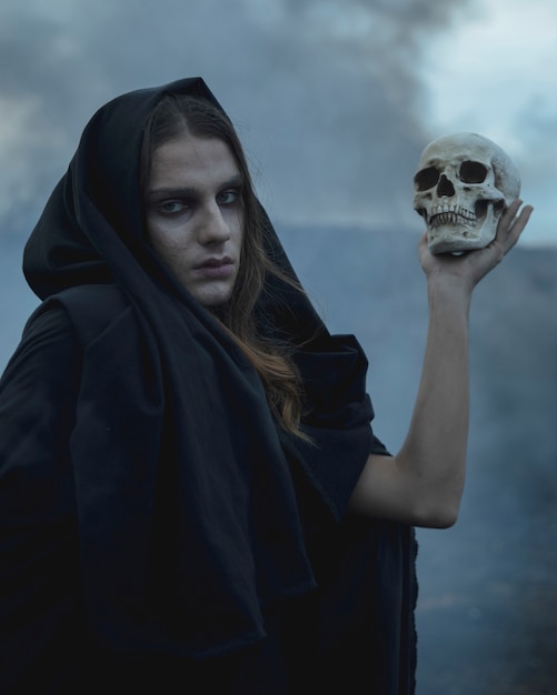 Man holding a skull in the dark and looking at camera