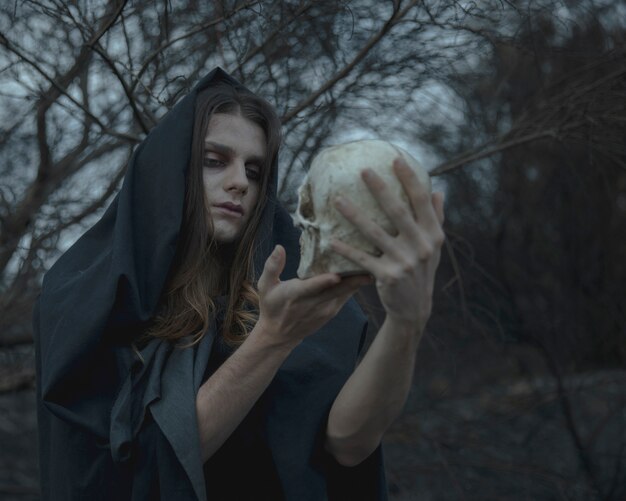 Free photo man holding a skull and looking at it