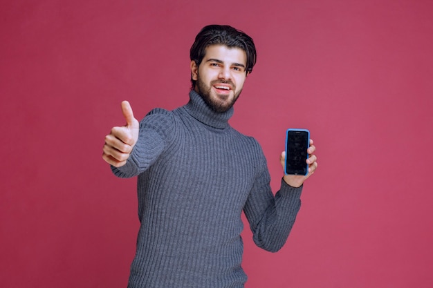 Man holding a smartphone and making good hand sign.