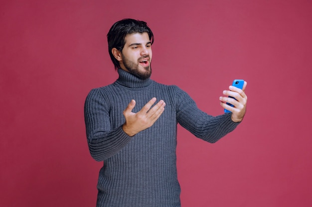 Man holding a smartphone, making a video call or taking selfie.