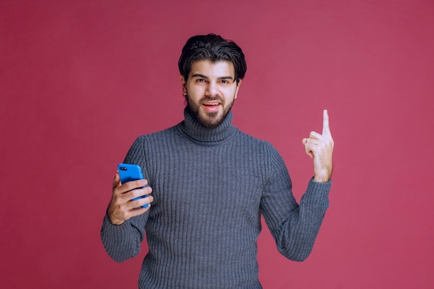 Man holding a smartphone and pointing up.