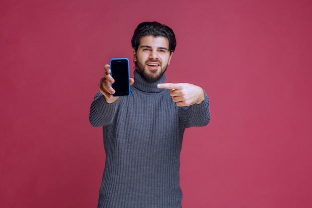 Man holding a smartphone and presenting it to the customers.