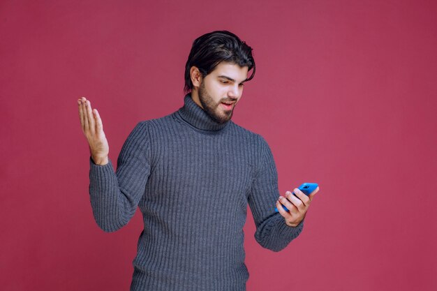 Man holding a smartphone, reading messages or texting.