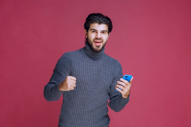 Man holding a smartphone and showing fist.