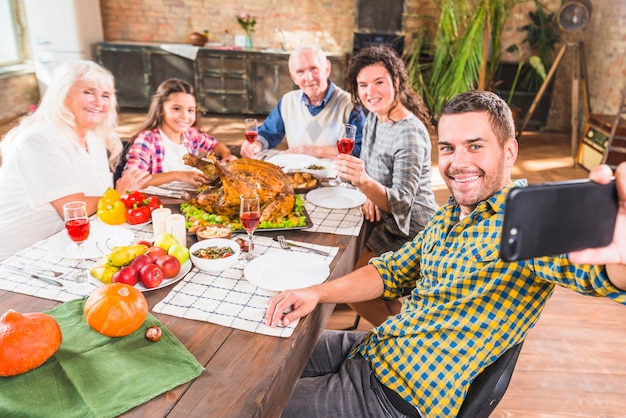 Man holding smartphone at table with family