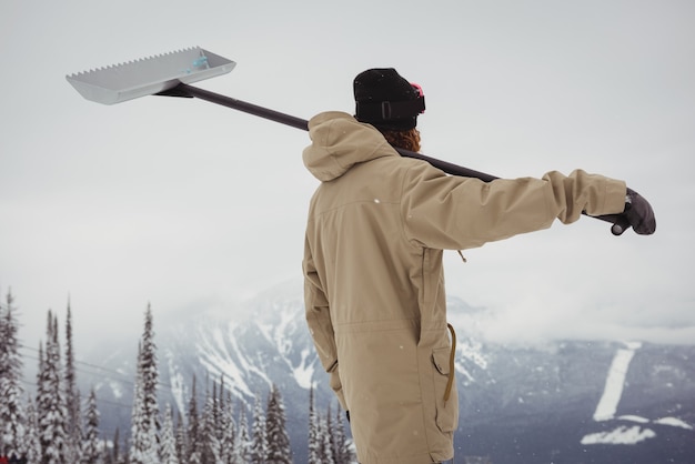 Uomo che tiene la pala da neve nella località sciistica