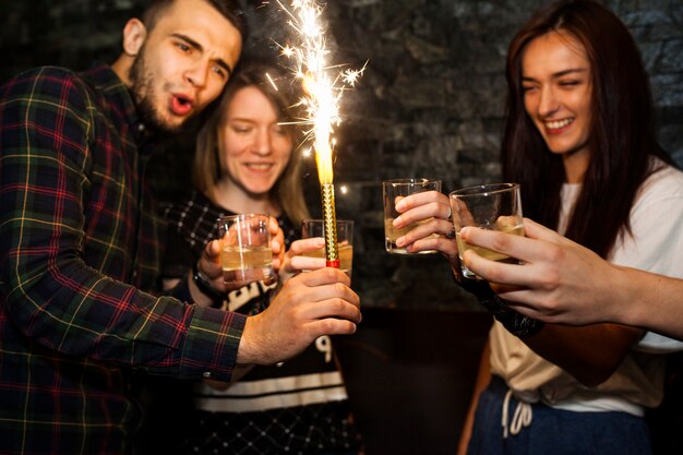 Man holding sparkle candle enjoying drinks with friends