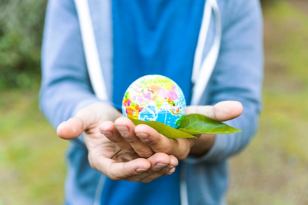 Free photo man holding sphere in palm of hand with leaf