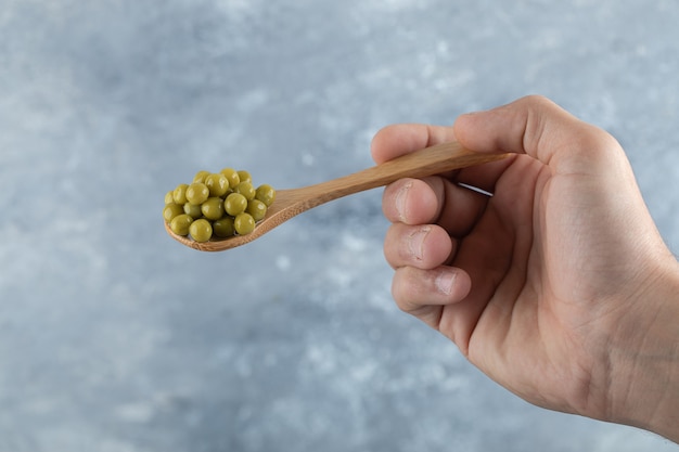 Man holding spoon with green peas