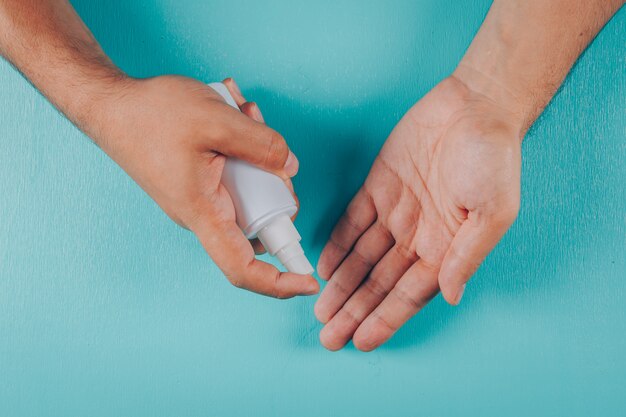 Man holding spray soap on a cyan blue