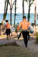 Free photo man holding a surfing board outdoors