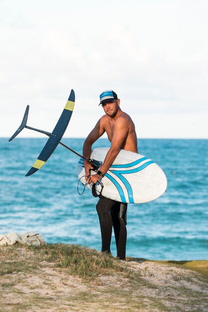 Мужчина держит доску для серфинга на открытом воздухе