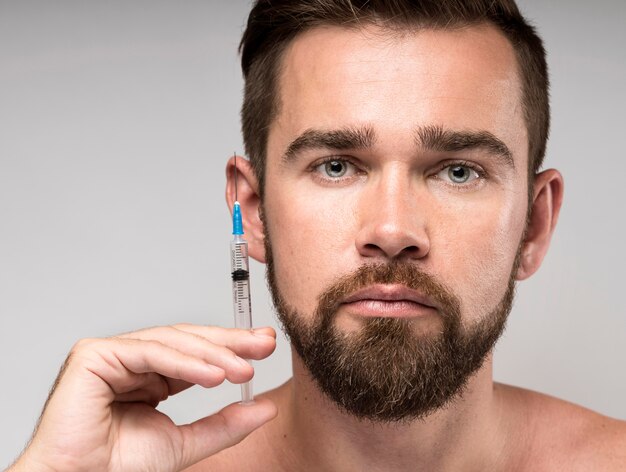 Man holding a syringe next to his face