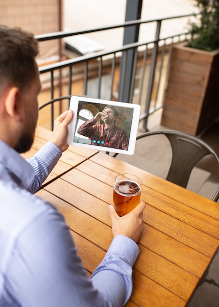 맥주를 마시는 동안 videocall에 대한 태블릿을 들고 남자