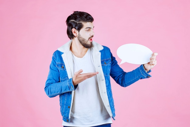 Foto gratuita uomo che tiene in mano una bacheca e la indica