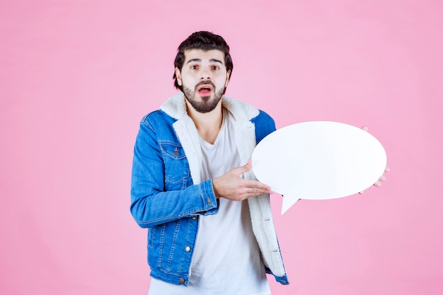 Free photo man holding a think board and pointing at it.