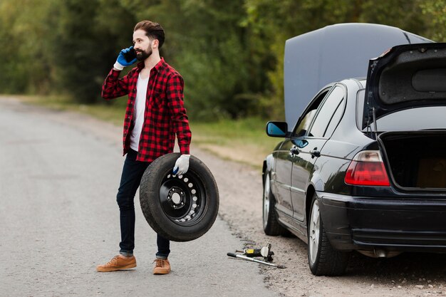 Man holding tire and talking on phone
