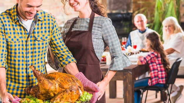 Man holding tray with roasted ham near woman 