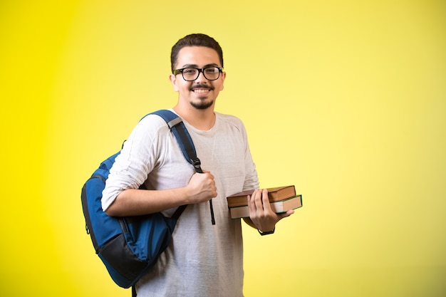 Man holding two book, looking straight and smiling.