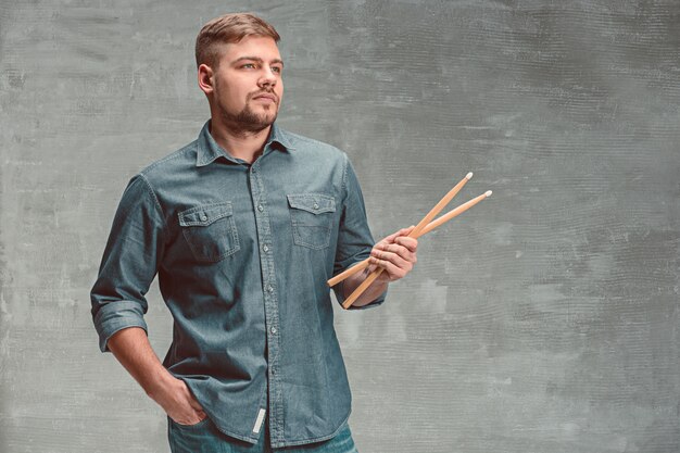 Man holding two drumsticks over gray