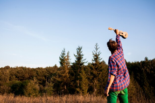 Man holding ukulele guitar in the air