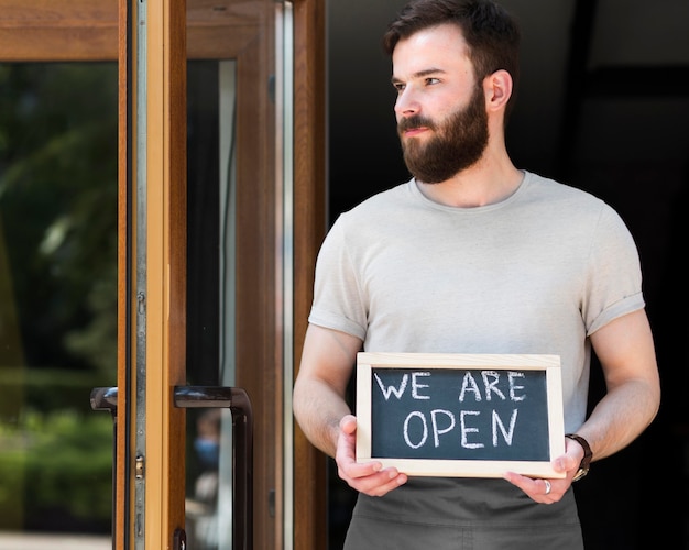 Free photo man holding we are open sign