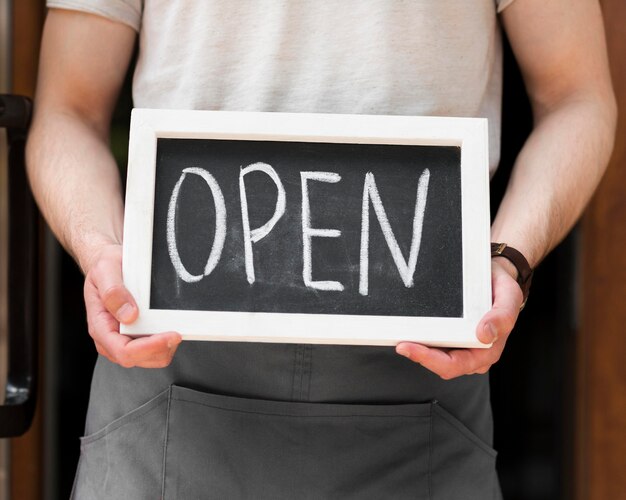 man holding we are open sign