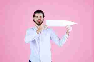 Free photo man holding a white arrow and showing east side.