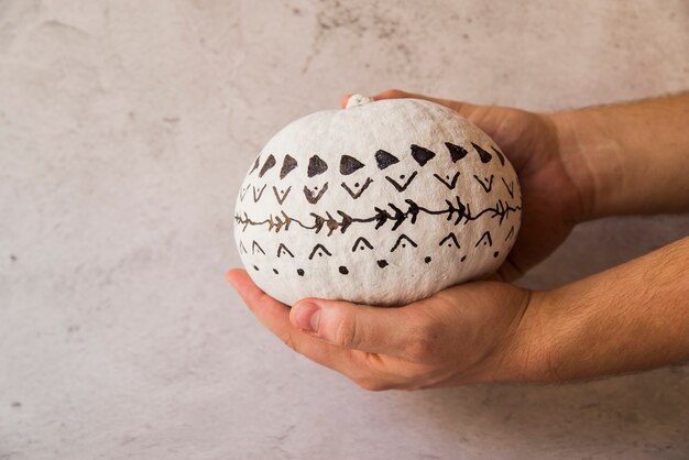 Man holding white pumpkin with black patterns