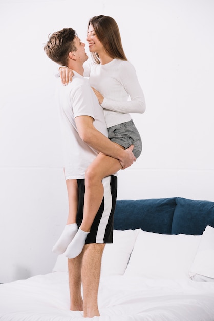 Man holding woman in arms on bed 