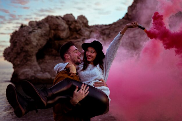 Man holding woman in arms with smoke bomb 