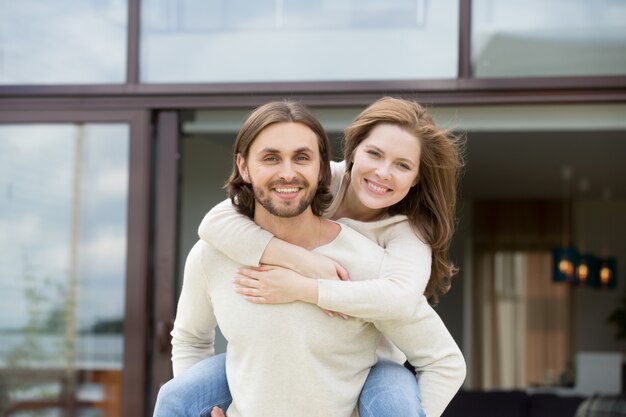 Man holding woman on back outdoors, looking at camera, portrait